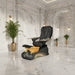 Black and gold pedicure chair with foot basin in a room setting.